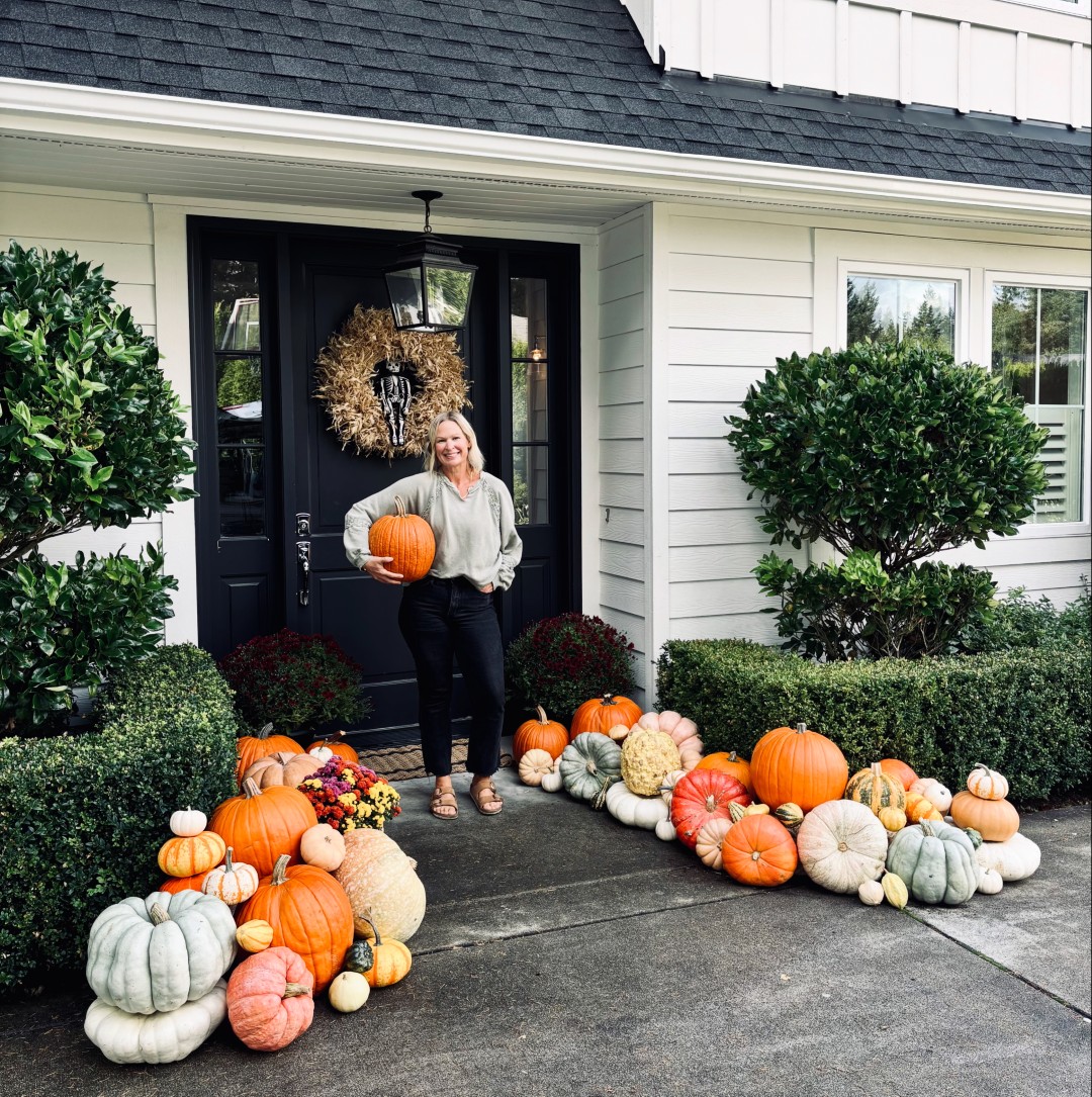 Team member with beautiful autumn porch decoration featuring pumpkins and wreath